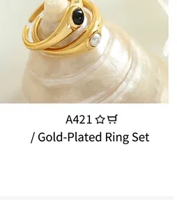 Detail of vintage gold open rings with black gemstone and white pearl on a seashell