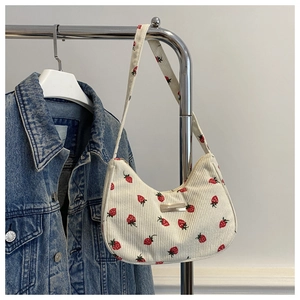 Detail of strawberry print corduroy tote bag hanging next to a denim jacket