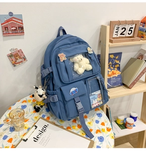Dettaglio zaino scuola blu con tasche trasparenti e ciondolo a forma di orso di peluche