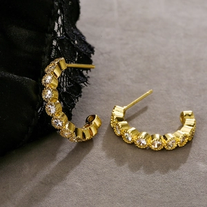 Eleganti orecchini a C placcati in oro 18K con zirconi scintillanti su sfondo di pizzo nero