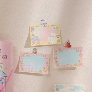 Detail of cute cartoon memo pads and acrylic clip on a textured beige wall