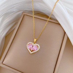 Close-up of golden necklace with pink heart pendant and small zircons on a jewelry box