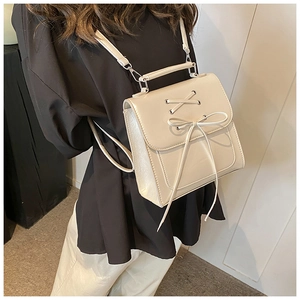Detail of cream PU leather backpack with decorative bow and crisscross lacing detail