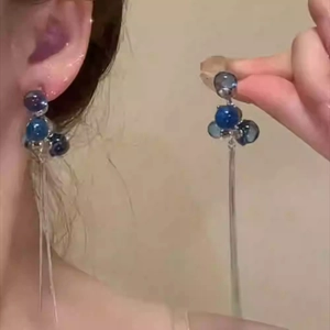 Detail of long tassel earrings with blue beads and silver needles on a model