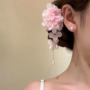 Dettaglio di un fermaglio per capelli a fiore in tessuto rosa con eleganti nappe di perle