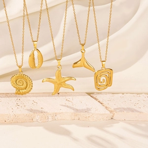 Golden sea snail starfish shell and whale tail pendant necklaces on white stone