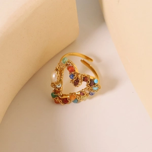 Detail view of heart-shaped gold chain ring with colorful beads on a beige base