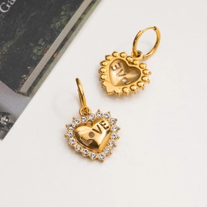 Close-up of golden heart earrings with white crystals and LOVE engraving details