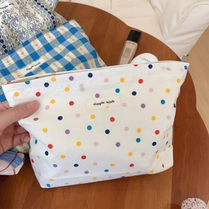 Detailed view of canvas makeup bag with colorful polka dots and simple wish label