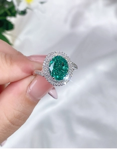 Detailed view of an oval green gemstone ring with a double halo of sparkling diamonds