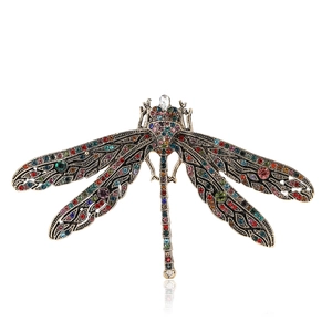 Vintage dragonfly brooch in bronze finish with colorful rhinestones on a white background
