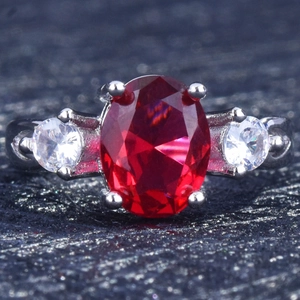 Classic silver ring featuring a large oval red ruby gemstone and clear side stones
