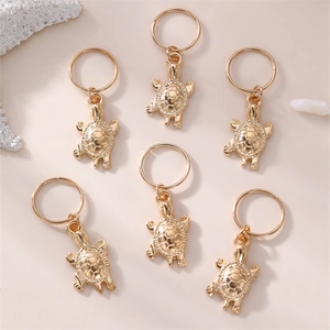 Detailed view of six golden turtle hair charms with embossed textures on a shell background