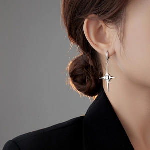 Detail of silver star-shaped earrings with white zircon on a female model's ear