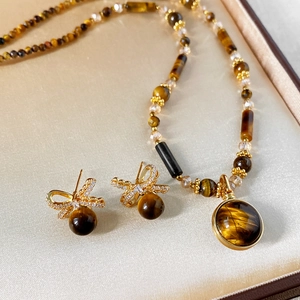 Macro shot of tiger eye stone jewelry set including bow earrings and necklace in a gift box