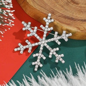Elegant silver snowflake brooch with sparkling white rhinestones on festive background