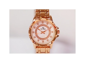 Macro detail of rose gold watch with sparkling diamonds and white mother-of-pearl dial
