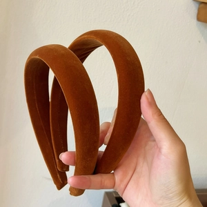 Detailed view of two thick brown velvet headbands with a soft matte texture for hair