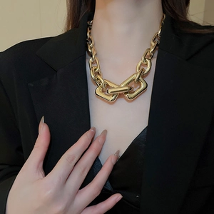Macro detail of chunky gold geometric chain necklace on model with black suit