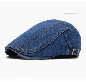 Detailed view of blue washed denim newsboy cap with yellow stitching and metal buckle