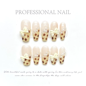 Detail of handmade brown polka dot press-on nails with 3D white bows and pearls decor