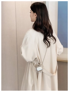 Close-up of silver mini chain bag crossbody style on a beige trench coat fashion look
