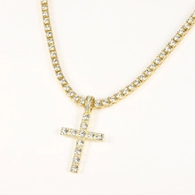 Close-up of gold-plated cross pendant and tennis chain with shimmering crystals