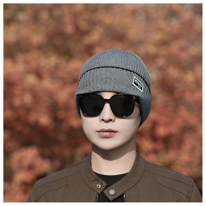 Close-up of grey ribbed knit beanie with black stripe detail and fashion label on side