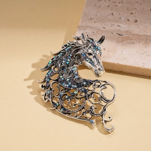 Detailed close-up of retro silver horse brooch with sparkling gradient rhinestones