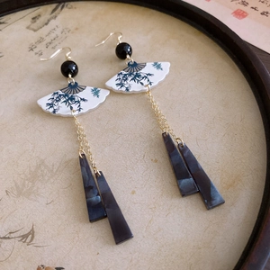 Detail of vintage drop earrings with blue jade-like pendants and bamboo pattern fans
