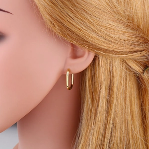 Side view of a gold-plated U-shaped rectangular hoop earring on a model