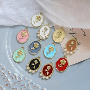 Detailed view of enamel rose pendants with gold plating and pearl accents on a plate