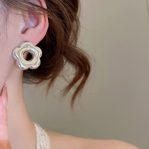 Gros plan sur des boucles d'oreilles fleur argentées polies portées par un mannequin