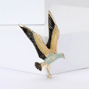 Colorful hummingbird enamel brooch with gold alloy edges shown on a white background