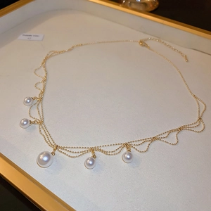 Detail of elegant gold-plated multi-layer pearl necklace on a white luxury display tray