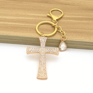 Detail of a gold cross keychain with sparkling rhinestones and a water drop pendant