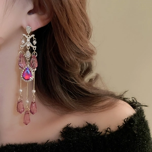 Close-up of vintage tassel earrings with pink crystal drop and pearl accents on model