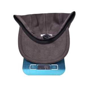 Adjustable brown suede baseball cap with interior drawstring shown on weighing scale