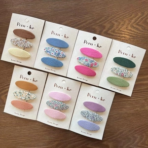 Floral and solid fabric BB hair clips set for kids with 7 color variations on wooden background