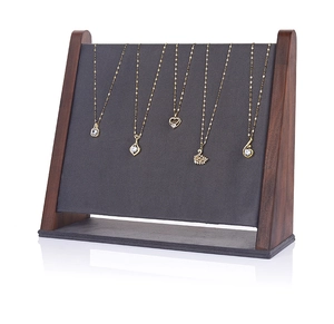 Detail of walnut wood necklace display stand with grey velvet panel and five gold hooks