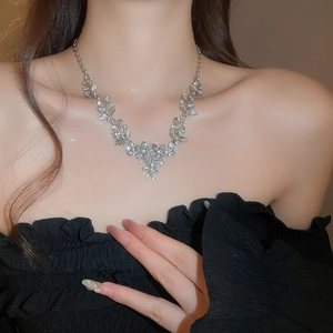 Close-up of a silver leaf and flower pendant necklace with sparkling diamonds on a model