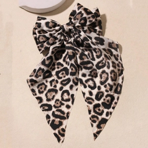 Elegant oversized leopard print fabric bow hair clip shown from a flat lay top perspective