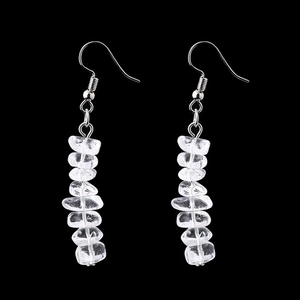 Macro shot of handmade crystal drop earrings with raw quartz stones on black background
