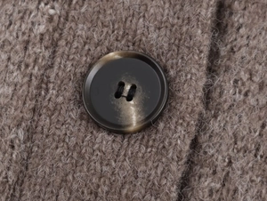 Detailed macro view of camel knitted fabric texture with a dark textured resin button