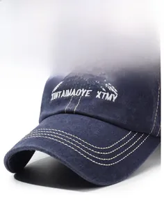 Detail of embroidered mountain logo and white lettering on navy washed denim baseball cap