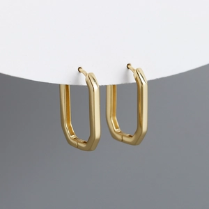 Macro shot of rectangular gold geometric hoop earrings with polished beveled edges