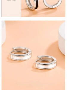 Detailed macro view of silver hoop earrings with white enamel finish on a warm backdrop