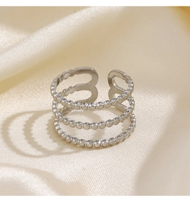 Detailed view of silver triple-layered beaded ring on champagne silk fabric background