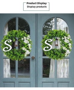 Detail showing artificial eucalyptus wreaths with white flowers and letter S on a blue door