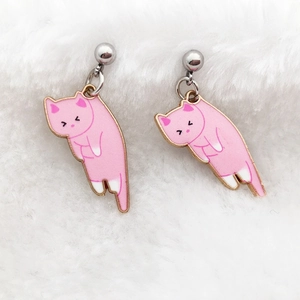 Detailed macro view of pink cat enamel earrings on soft white plush fabric background